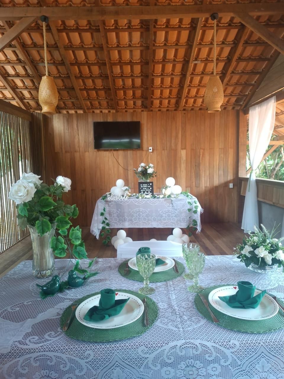 Detalhe de mesa posta para evento, com jogo americano verde e taças