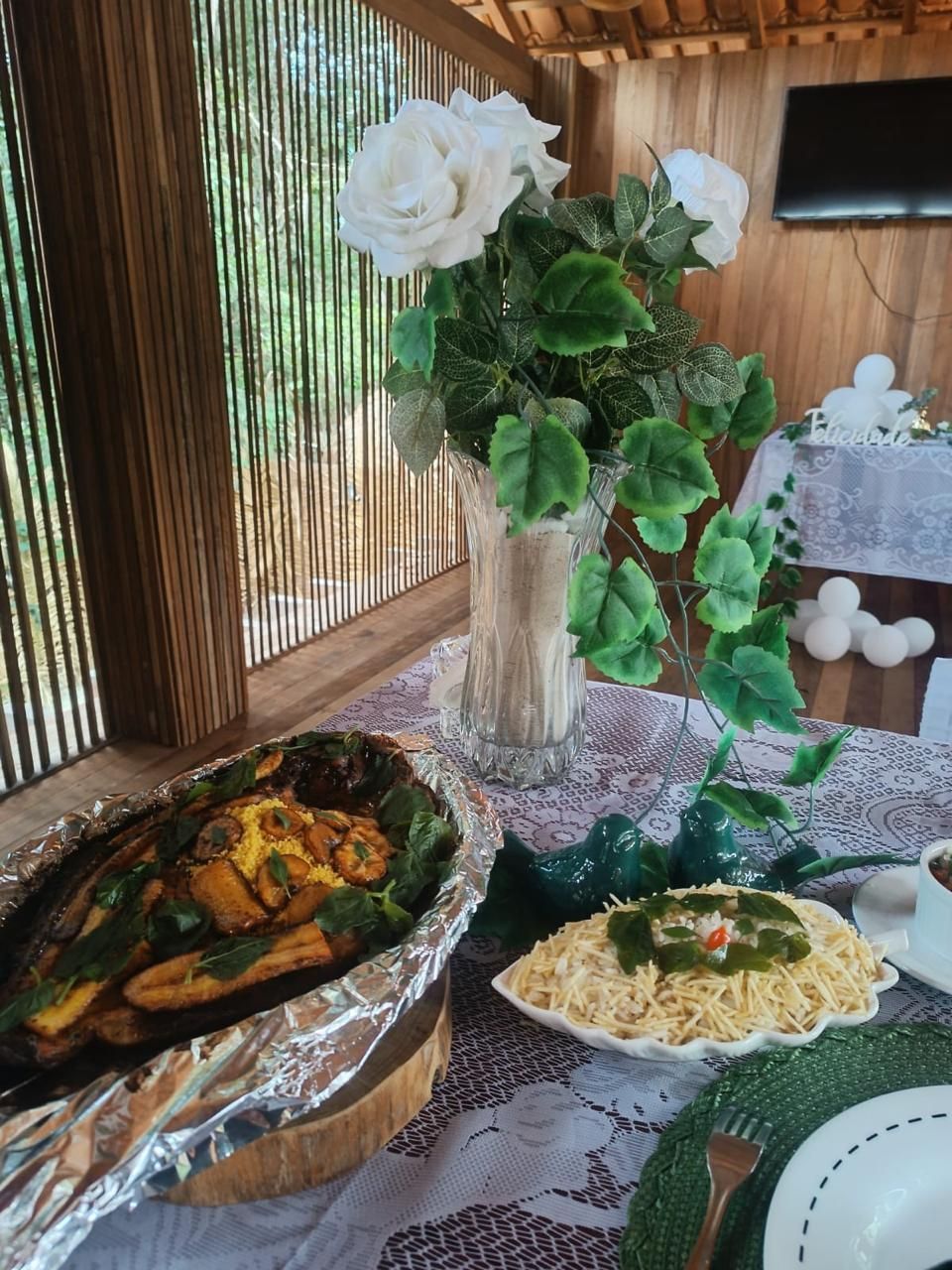 Mesa de evento decorada com rosas brancas e enfeites de pássaros em cerâmica verde