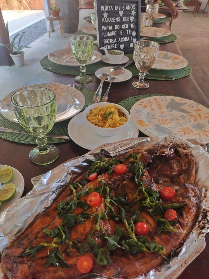Peixe assado com folhas e tomates servido à mesa, com arroz e taças